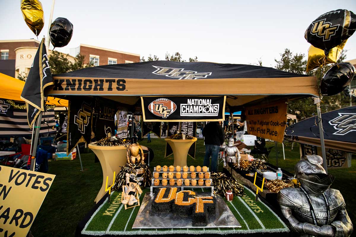 A UCF tailgate tent with balloons, UCF shaped cakes and National Champions banner