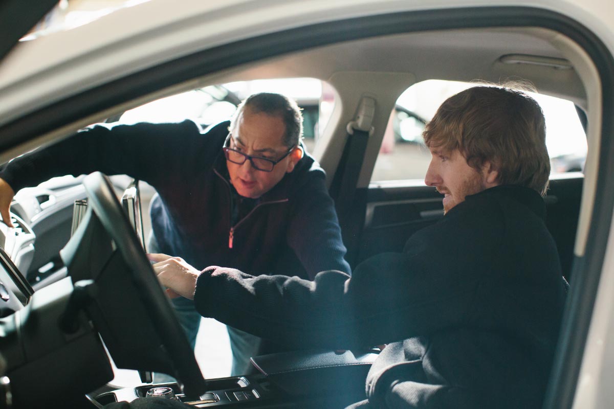 Two men check out the interior of a car.