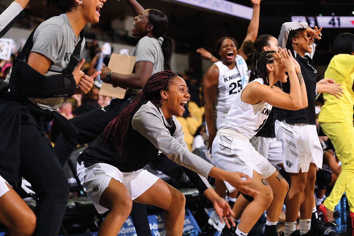 A group of female basketball players cheer.
