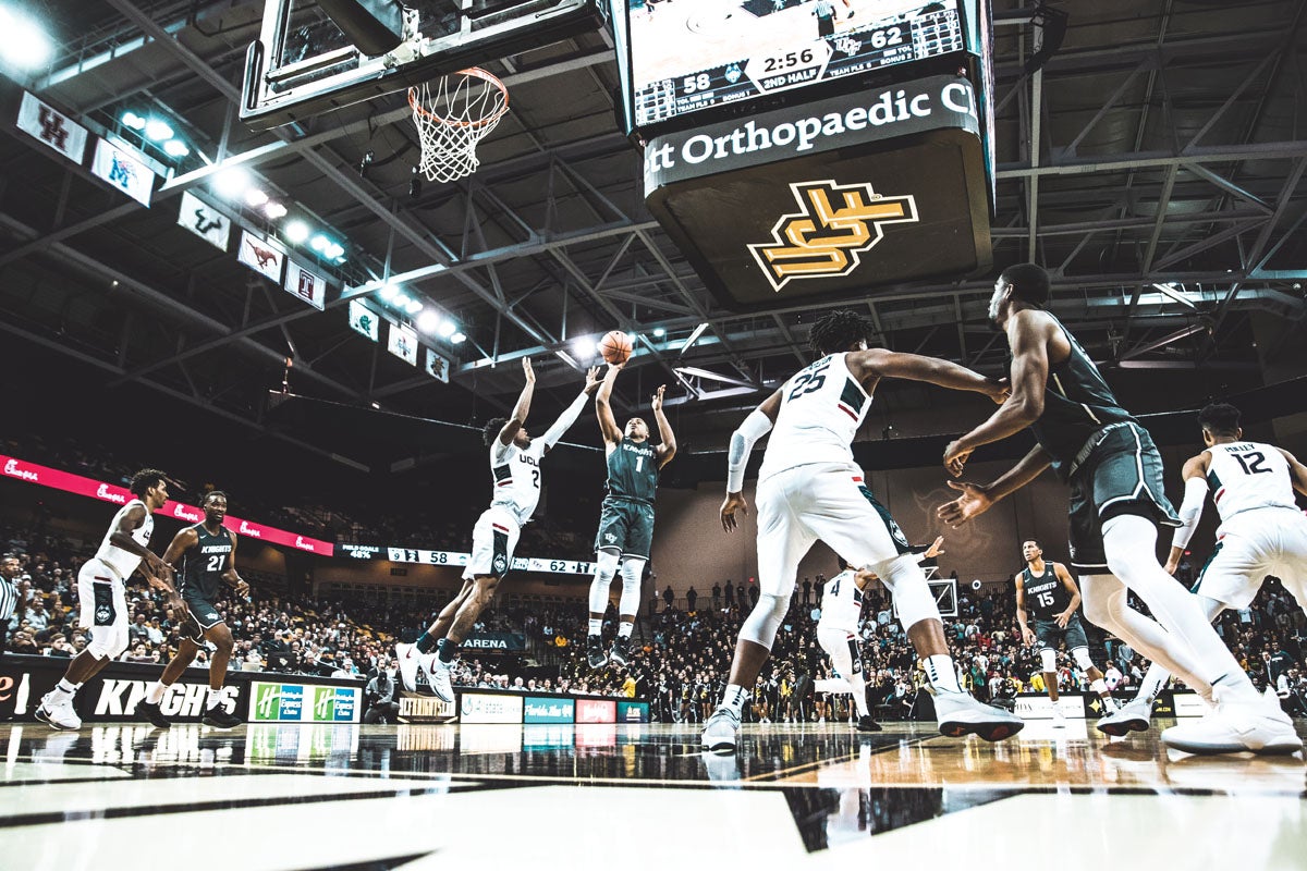 A UCF basketball player tries to stop a player from the opposing team from making a basket.