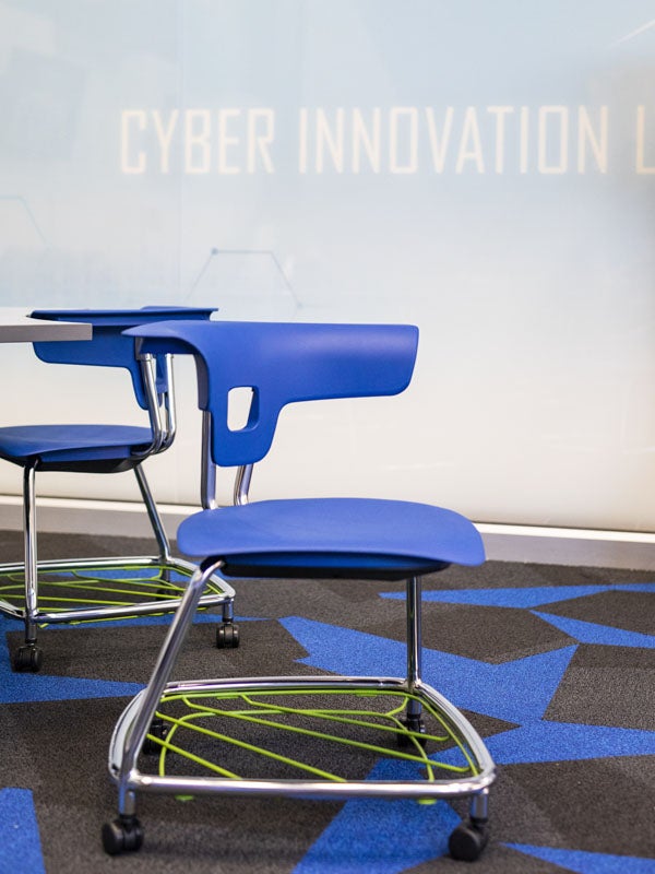 Green baskets sit beneath blue plastic chairs that are on wheels.