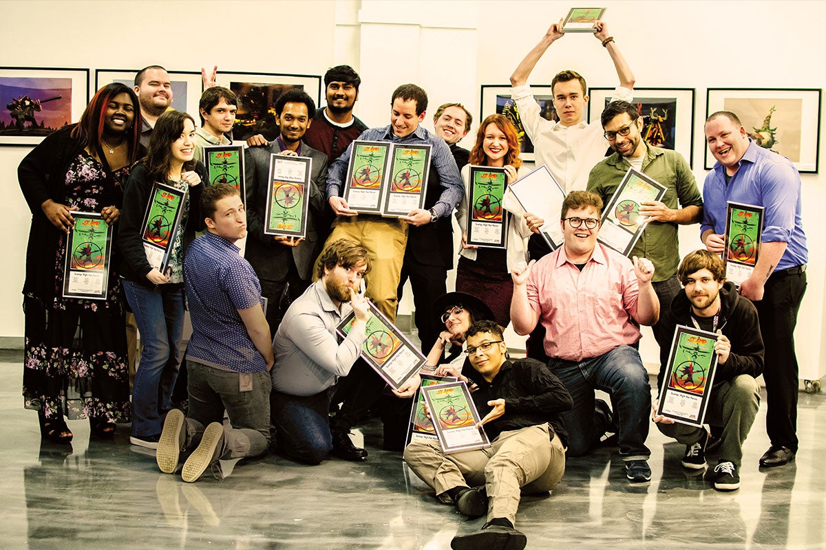 A group of students in various poses hold up awards.