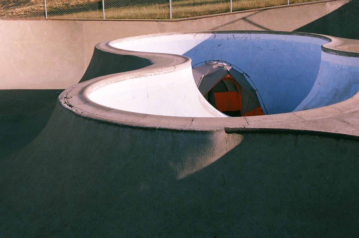 An orange tent in a BMX concrete bowl.