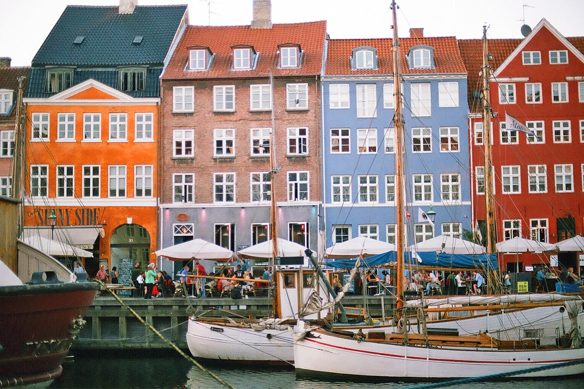 Boats sit on the water in front of some colorful buildings.