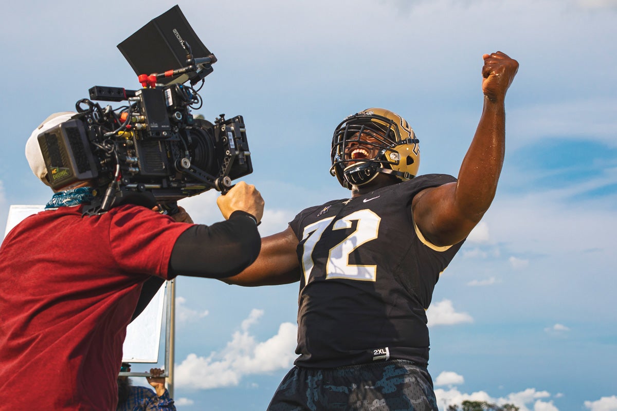 A cameraman records a football player