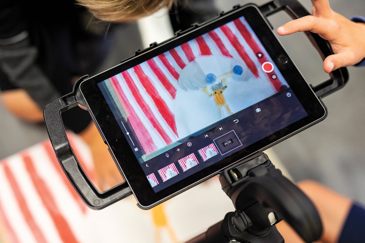 A child takes a photo of a drawing on a tablet.