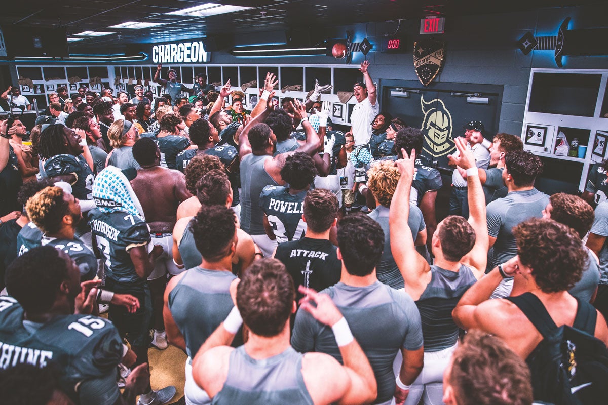 Head Football Coach Josh Huepel throws a football in the locker room after a game.