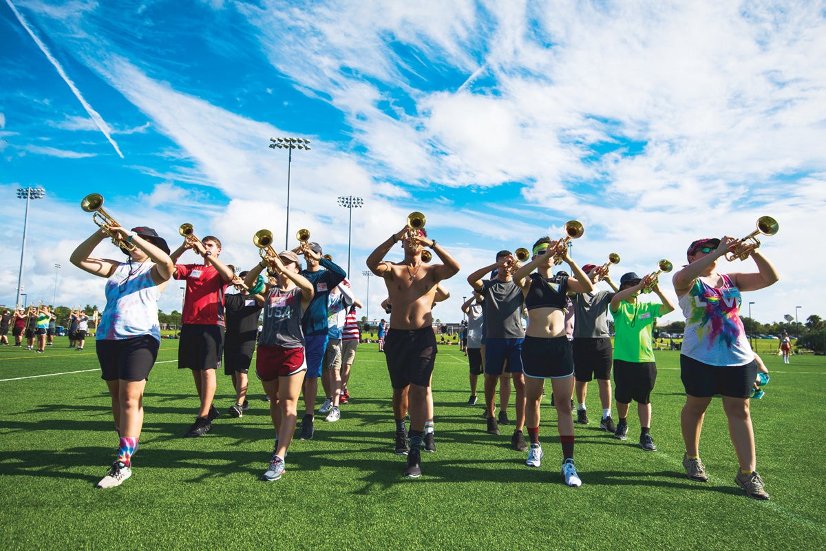 The trumpet section practices playing on a field.