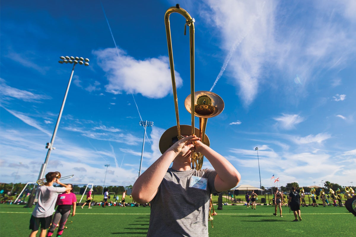 A trombone player plays on a field.