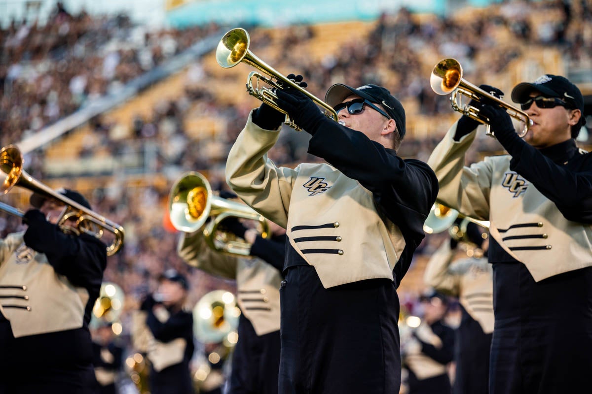 Trumpet players perform on the filed during a football game. 