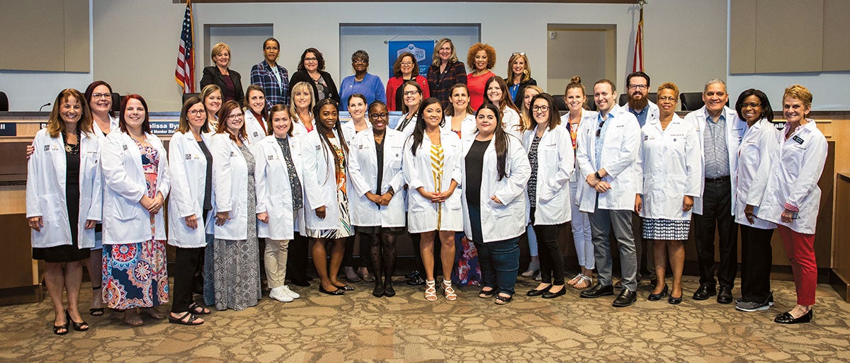 A group of students in white coats pose for a picture.
