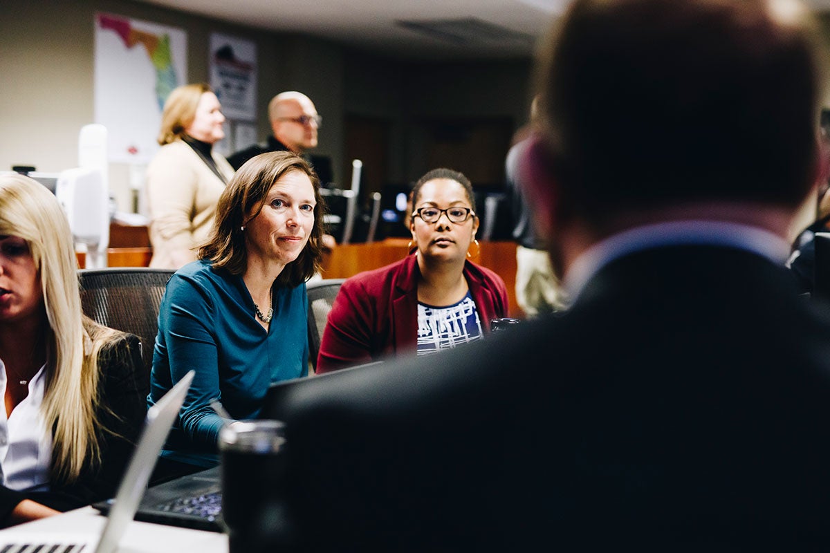 Two women face the camera while a man has his back to it.