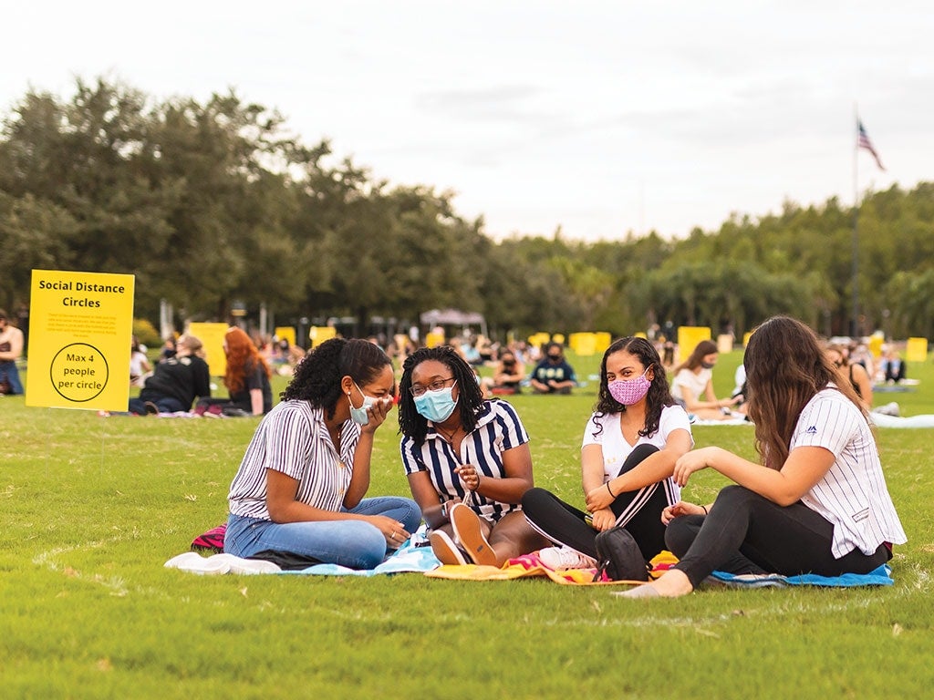 a group of four students physically distancing on the lawn