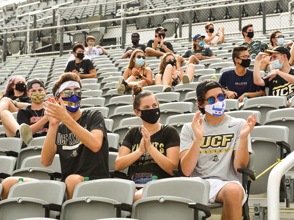 students sitting in physically distanced groups in stadium stands students sitting in physically distanced groups in stadium stands