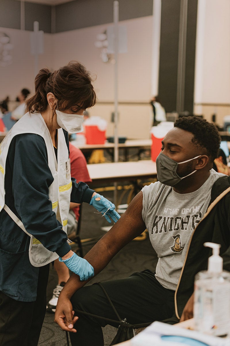 A student receives a COVID-19 vaccine from a UCF Student Health Services employee