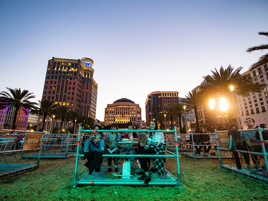 Groups of people sit outdoors in physically distant sections