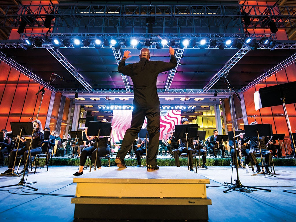 A man conducting a band on stage