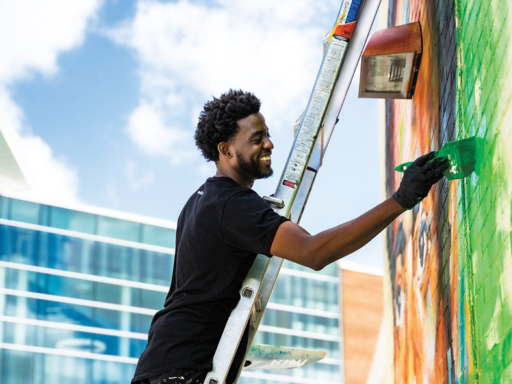 Peterson Guerrier smiles while painting