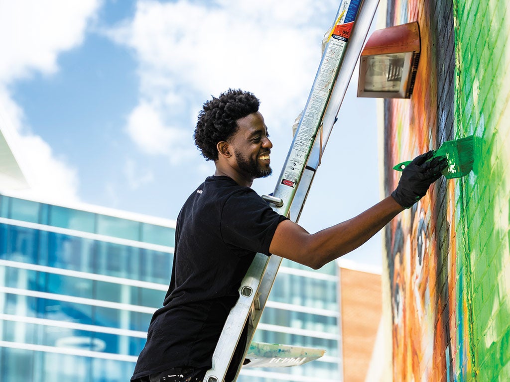 Peterson Guerrier smiles while painting Peterson Guerrier smiles while painting
