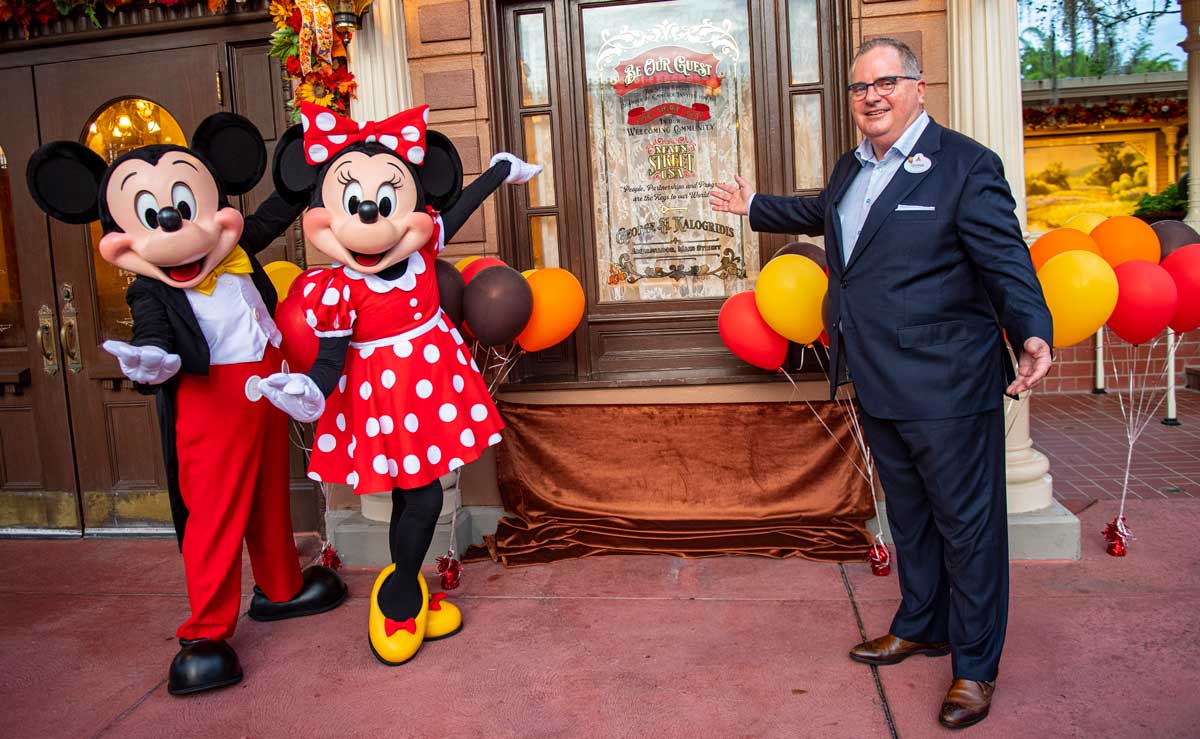 George Kalogridis poses with Mickey and Minnie Mouse in front of his window on Disney's Main Street