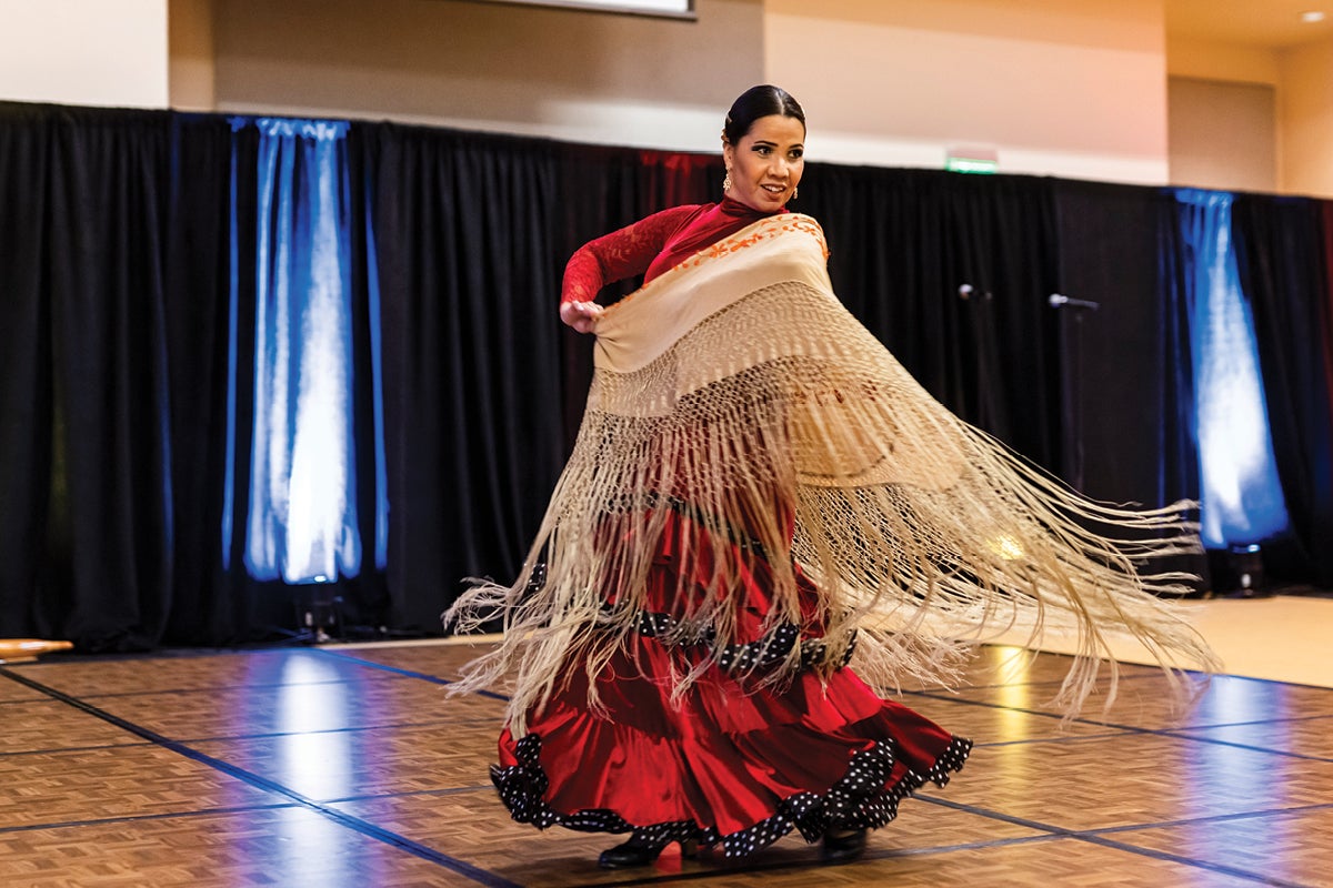 A Hispanic/Latinx dancer in traditional clothing performs