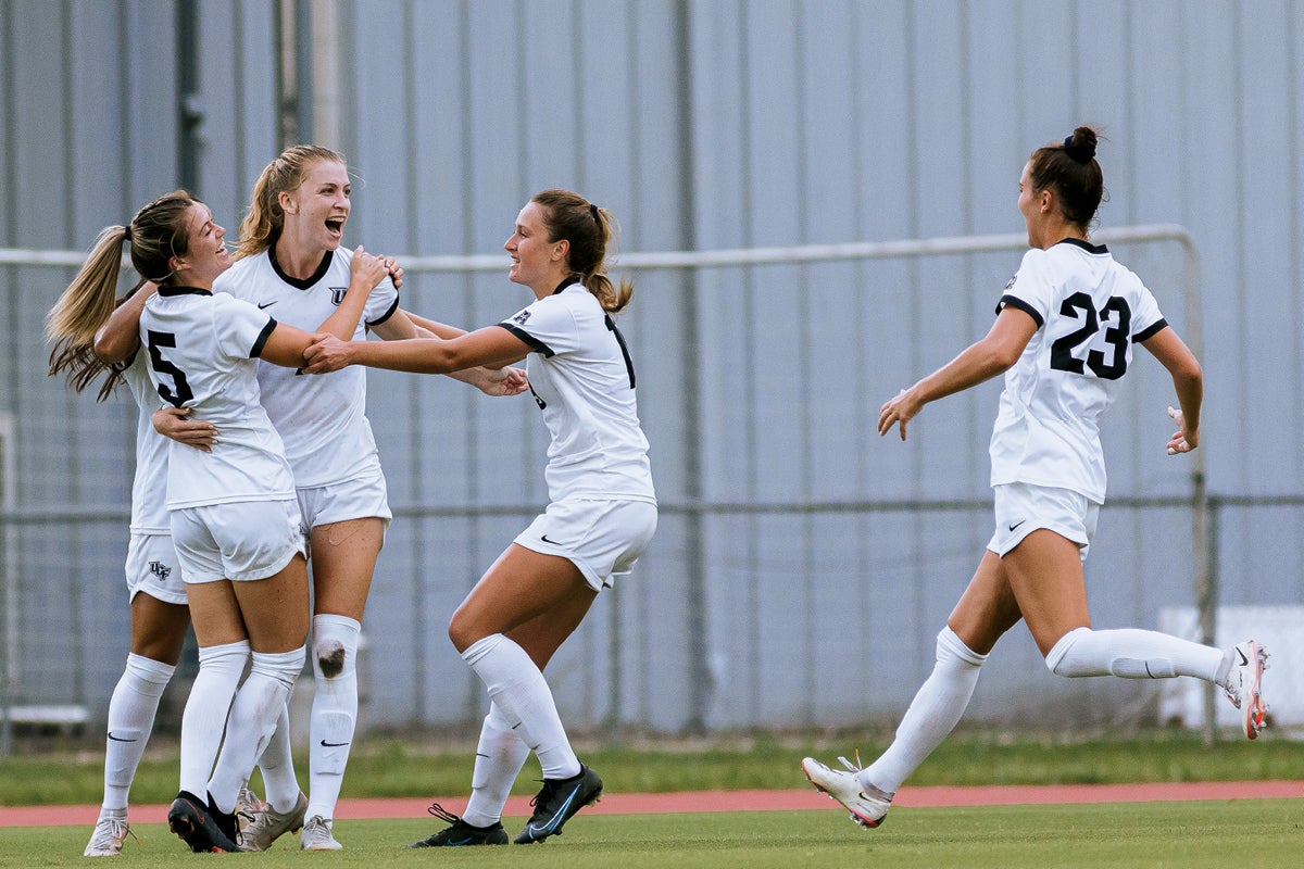 UCF women's soccer players hug after a player scores a goal