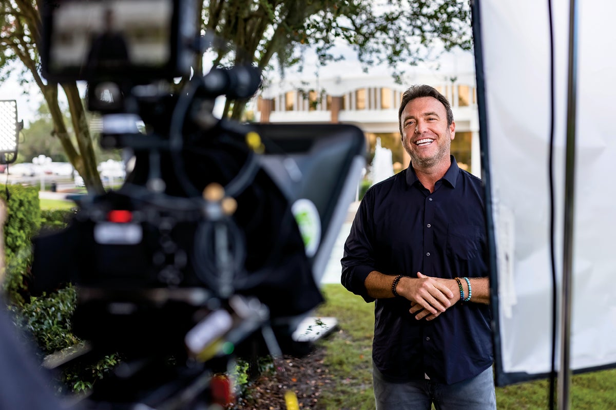 Alex Boylan speaks to a camera while standing in front of the Reflecting Pond