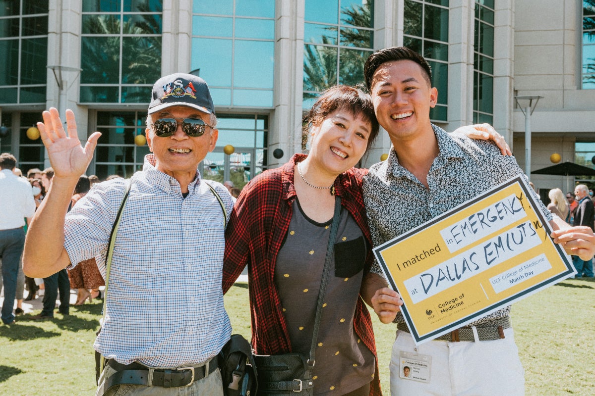 Michael Chiang holds a match day sign while posing for a photo with his parents.