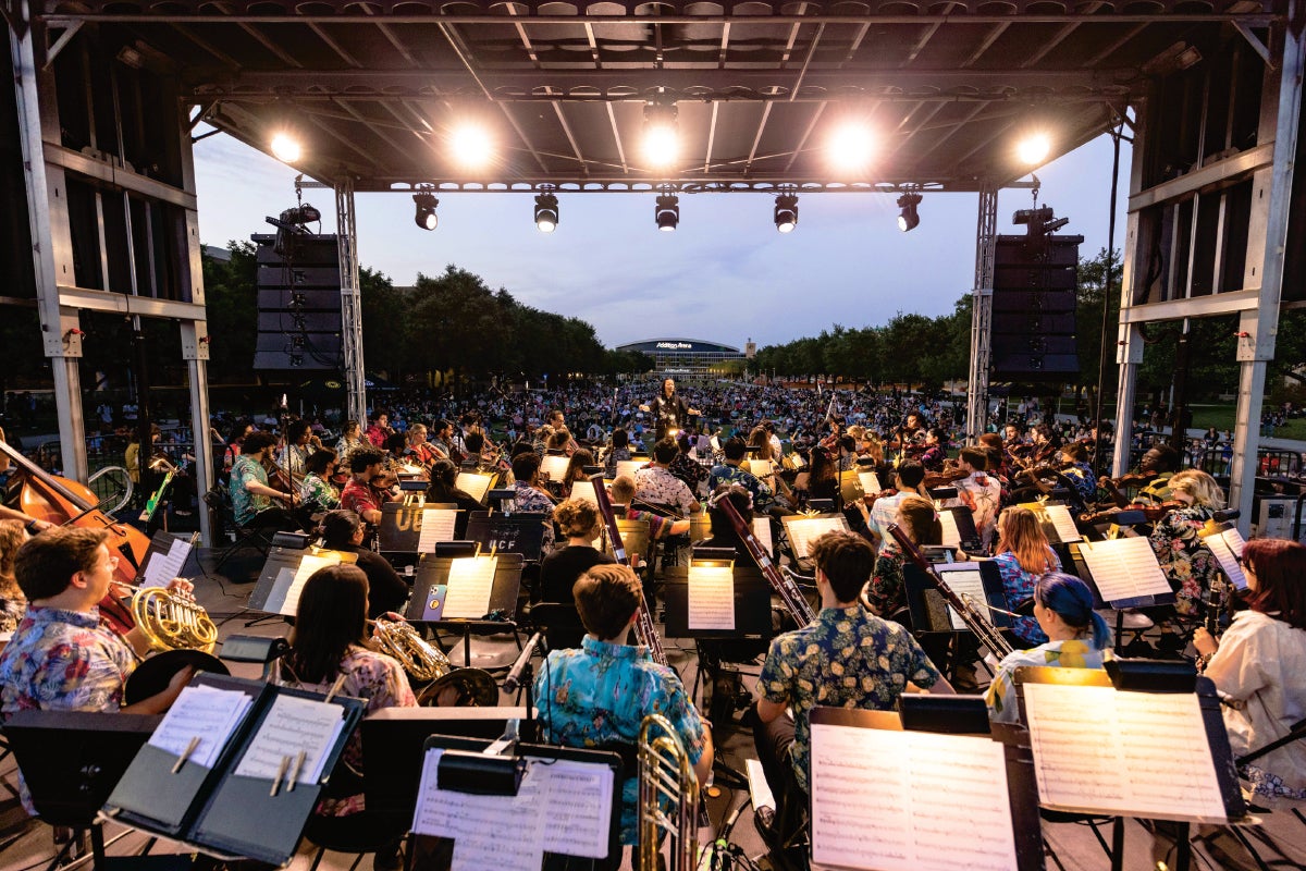 A group of students playing in the UCF Symphony Orchestra on Memory Mall for a crowd.