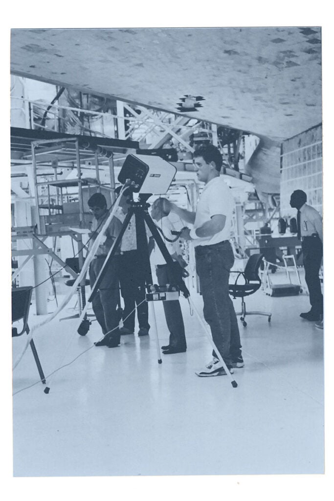 A black and white photo of men working in the Space Shuttle landing facility.