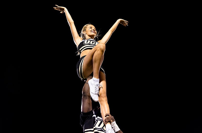 A UCF cheerleader holds another cheerleader in the air.