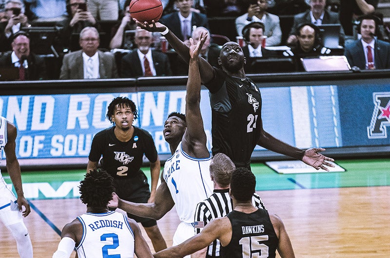 Tacko Fall hitting a basketball as Zion Willamson tries to grab the ball.