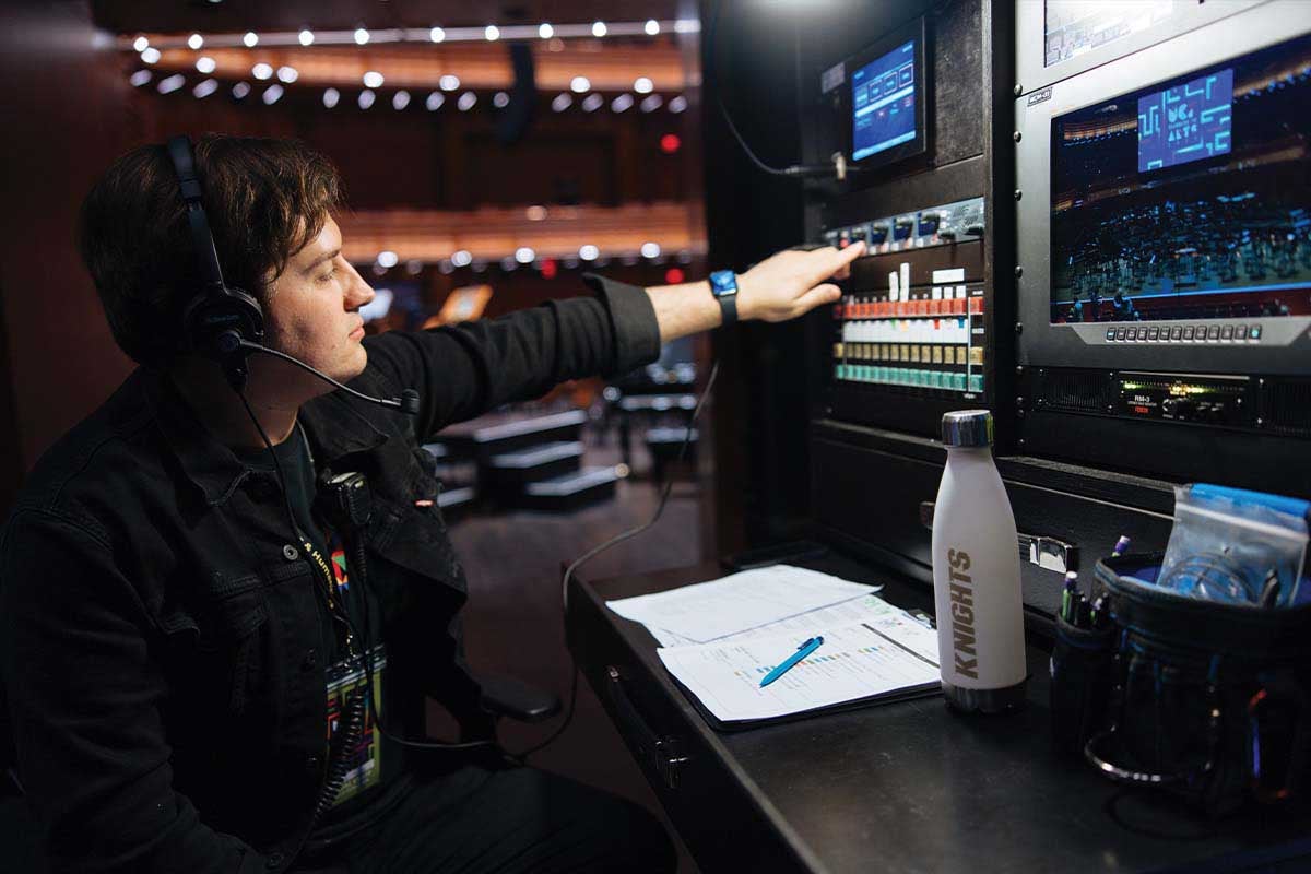 Student touches button on equipment as he works backstage during UCF Celebrates the Arts