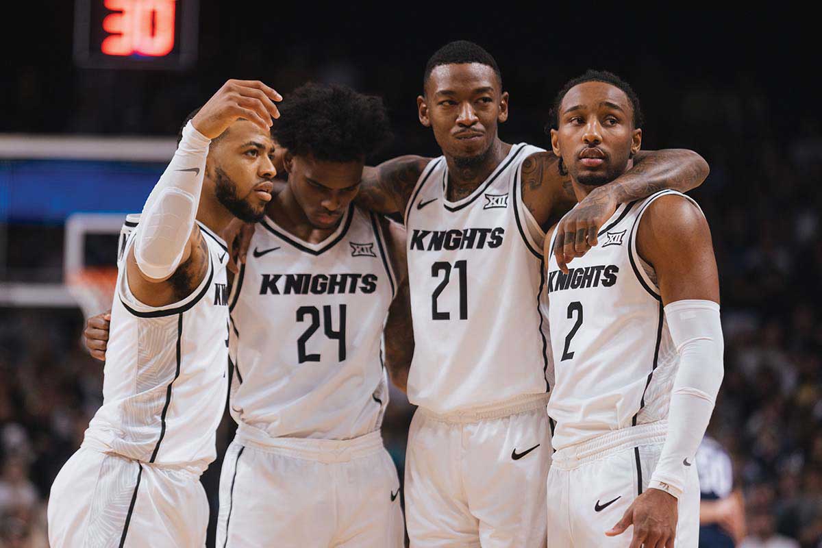 UCF men's basketball players Darius Johnson, Jaylin Sellers, C.J. Walker and Shemarri Allen share a group hug on the basketball court.