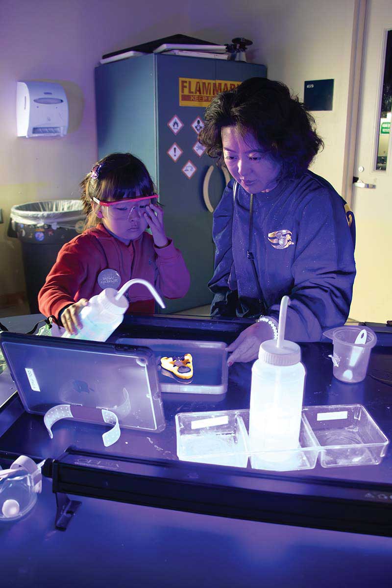 A child holds a wash bottle while working with a researcher