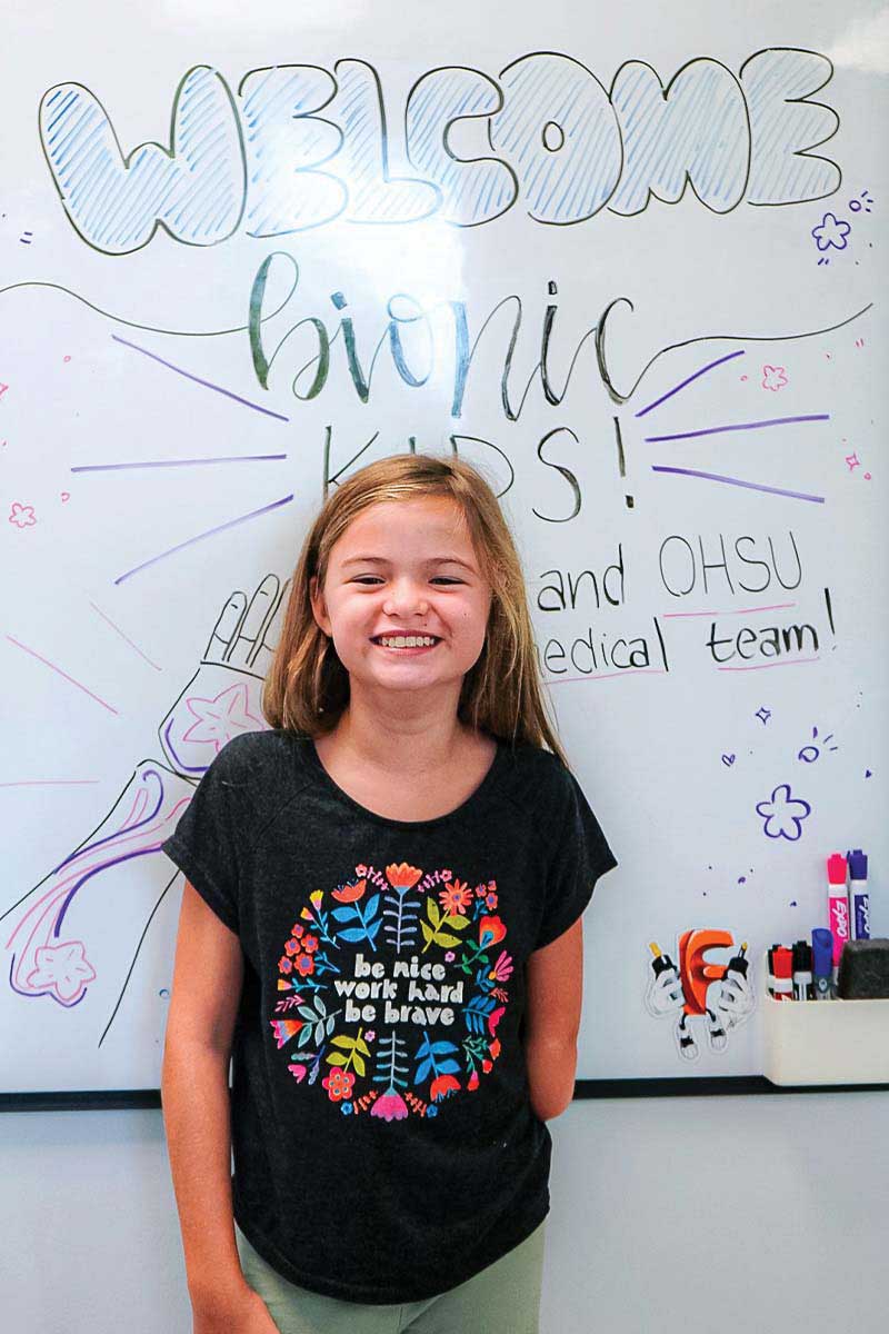 A bionic kid standing in front of a whiteboard that says Welcome