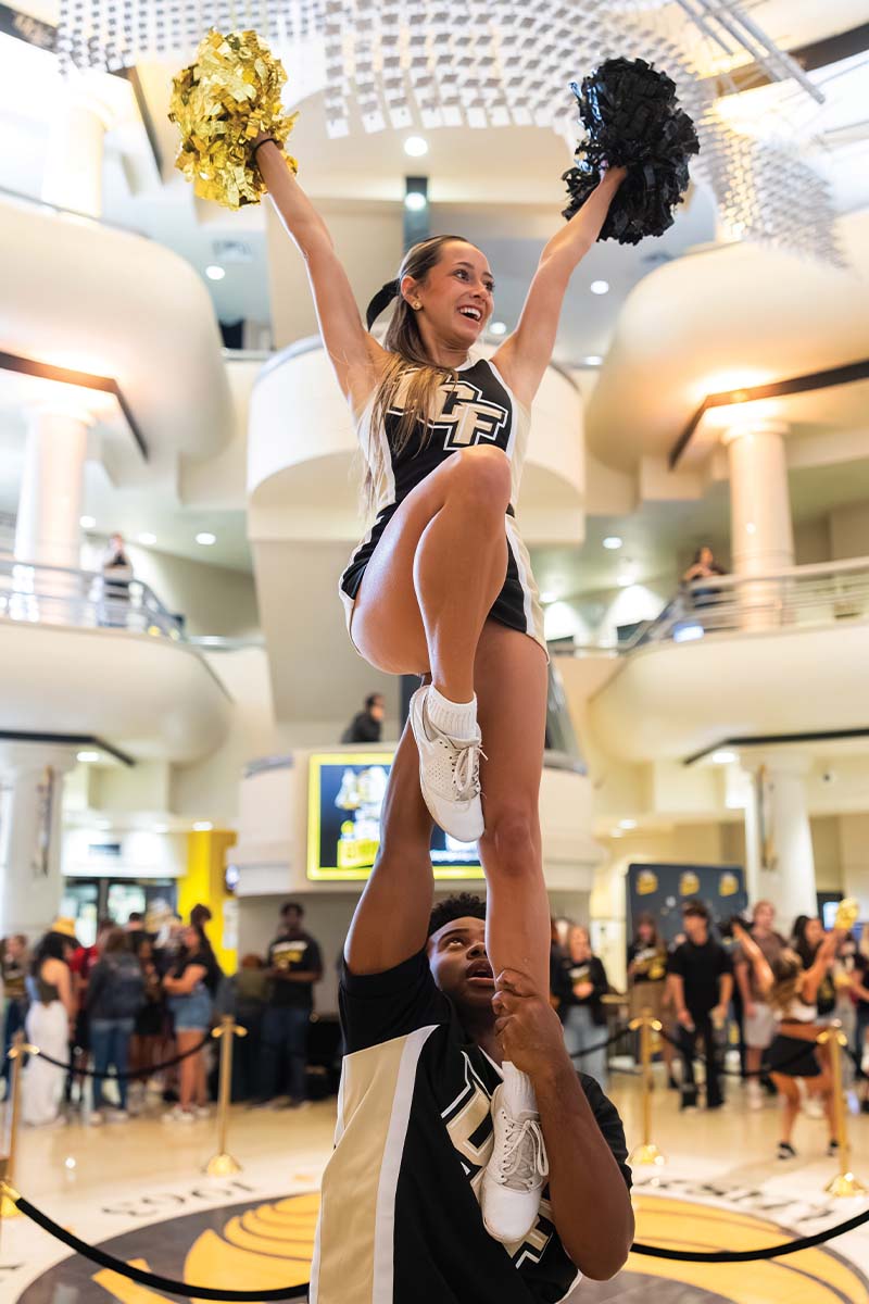 A cheerleader holds another cheerleader in the air