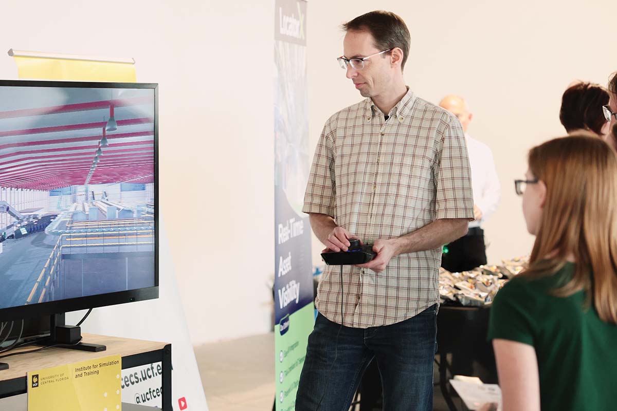 A man controls a video game while a student watches