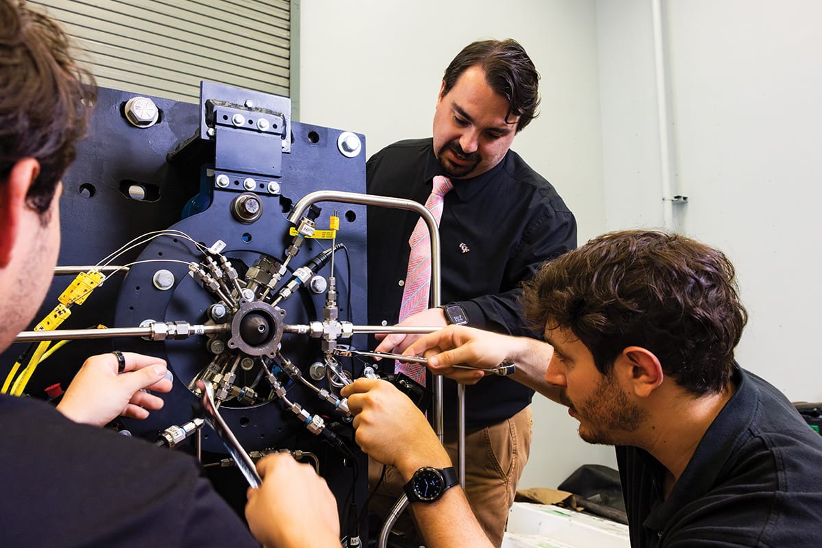 A group of researchers adjusts instruments on a circular mechanical device.