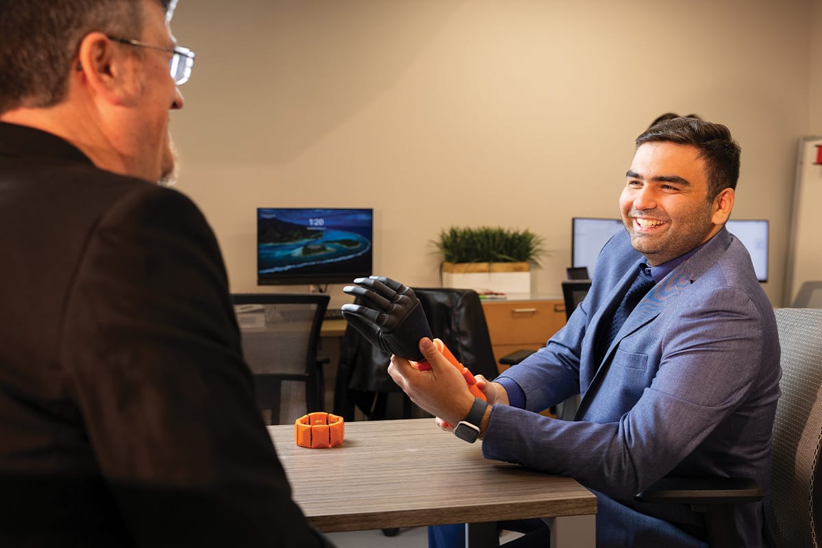 Professor of Philosophy Jonathan Beever (left) and Assistant Professor of Electrical and Computer Science Mohsen Rakhshan (right) discuss a human-machine interface technology prototype for a project supported by Meta.