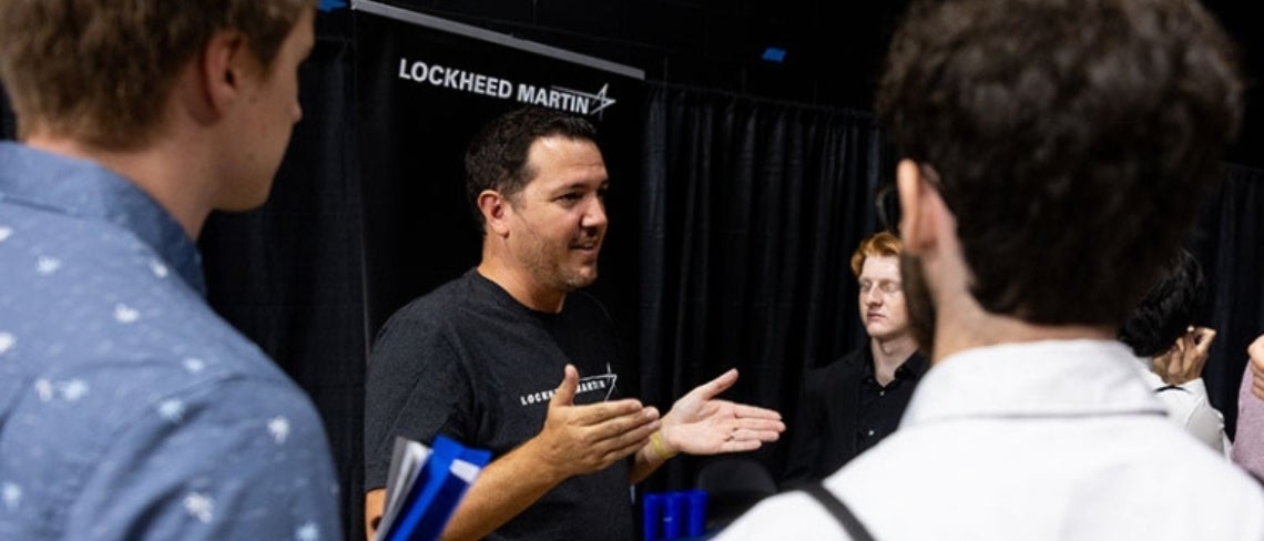 Lockheed Martin recruiter speaks to a small group of students at a career fair event